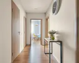 Jasny, neutralny jaki kolor do przedpokoju? Jasne ściany, drewniane drzwi i podłoga tworzą przytulną atmosferę.