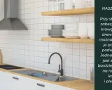 Nowoczesna kuchnia z drewnianym blatem, pod którym zamontowano zlew podwieszany. Białe płytki i stalowy okap tworzą czysty design.
