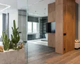 Nowoczesny salon z elementami drewna, w tym pionowa ściana z desek. Wnętrze rozświetla kominek i rośliny.