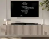 Nowoczesna, wisząca szafka RTV z telewizorem i lampką.
