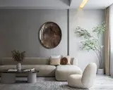 Minimalizm w domu: beżowa sofa, okrągłe lustro i drzewko w donicy tworzą spokojną przestrzeń.
