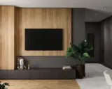 Nowoczesna ściana za telewizorem z drewnianymi panelami i minimalistyczną szafką. W tle widać korytarz z drzwiami.
