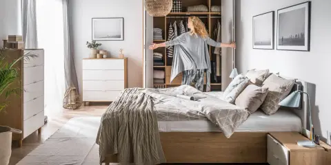 Stylowa aranżacja komody w sypialni, z otwartą szafą i kobietą wybierającą ubrania.