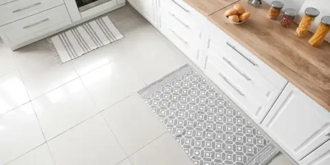 Dwa dywaniki na jasnej podłodze w kuchni: jeden w paski, drugi z geometrycznym wzorem.