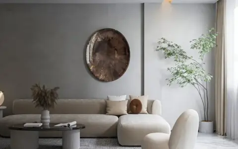 Minimalizm w domu: beżowa sofa, okrągłe lustro i drzewko w donicy tworzą spokojną przestrzeń.