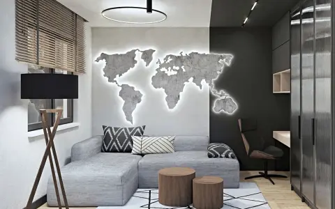 Nowoczesny męski pokój inspiracje: szara kanapa, podświetlana mapa świata na ścianie, drewniane stoliki i biurko.