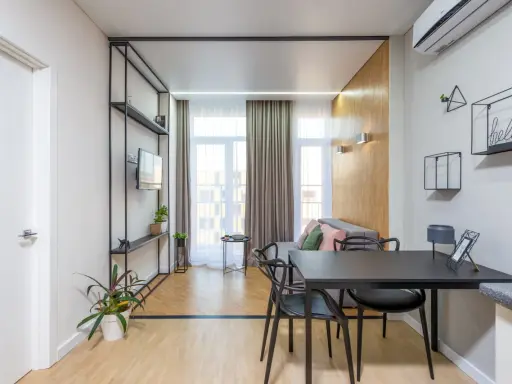 Nowoczesny podział pokoju z jednym oknem. Stół z krzesłami, sofa, regał z TV i rośliny.