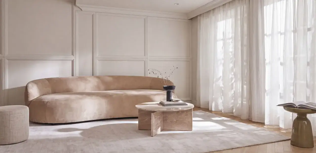 Elegancki salon w odcieniach beżu i kolor ecru jaki to kolor &ndash; miękka sofa, okrągły stolik i jasne zasłony tworzą przytulną atmosferę.