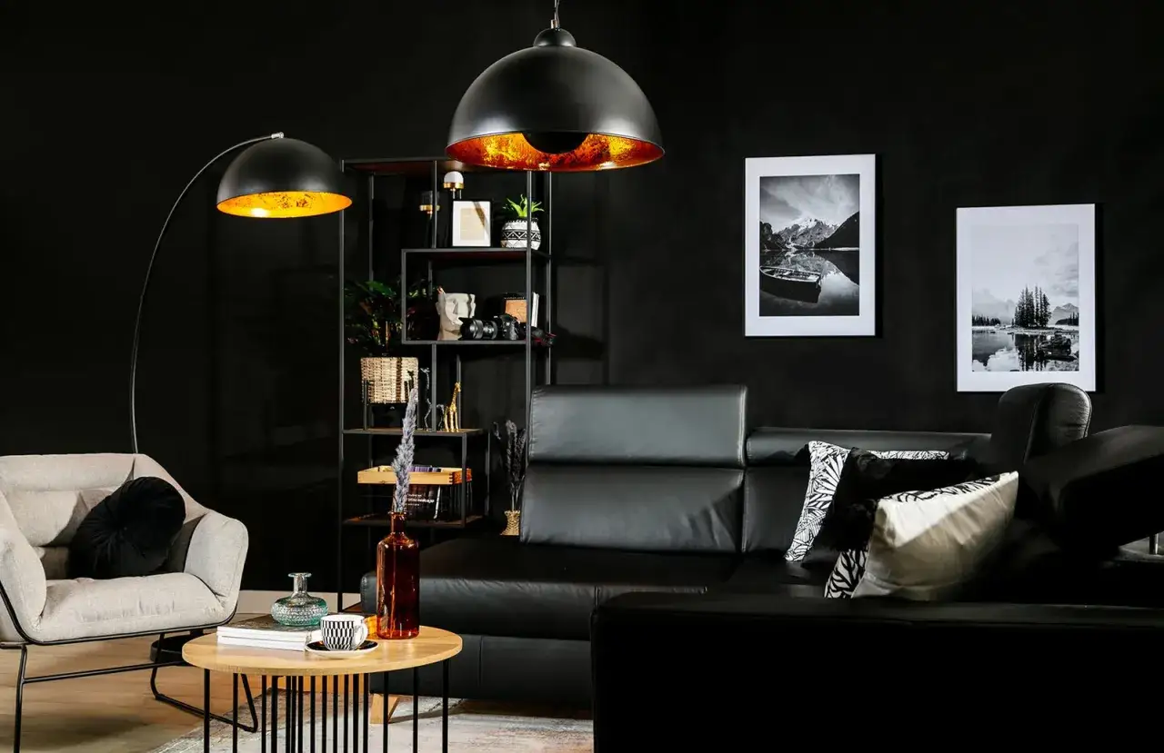Męski pok&oacute;j inspiracje: czarna sk&oacute;rzana kanapa, szary fotel, designerskie lampy i grafiki g&oacute;rskie.